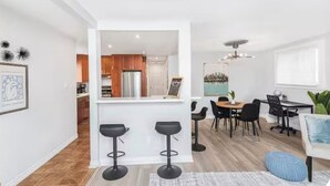 A modern kitchen with a central island, a dining area with a table and chairs, and a living area with a sofa and a coffee table.
