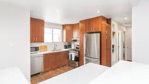 A modern kitchen with wooden cabinets, stainless steel appliances, and a white countertop.