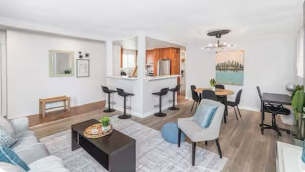 A modern living room with a sofa, coffee table, and a dining area with chairs and a table.