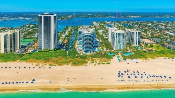 A coastal cityscape with high-rise buildings, a beach, and a marina.