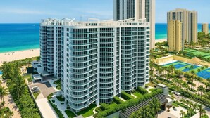 A high-rise hotel with multiple floors, a pool area, and a beach view.