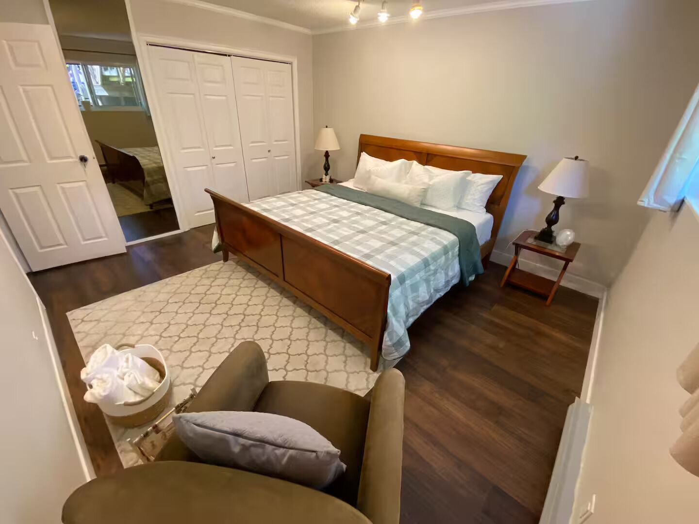 Une chambre à coucher avec un lit, des tables de chevet, une chaise, un tapis et une armoire.