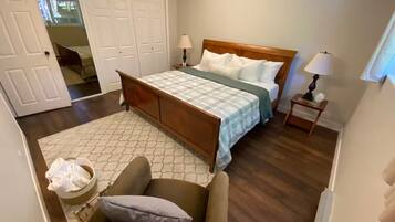 Une chambre à coucher avec un lit, des tables de chevet, une chaise, un tapis et une armoire.