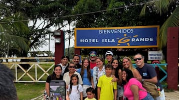 Un grupo de personas posando frente a un letrero que dice "BIENVENIDOS HOTEL ISLA GRANDE".