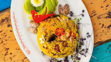 A plate of food with yellow rice, avocado slices, and garnishes on a white plate.