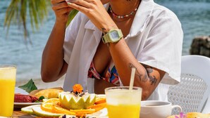A person sitting at a table with a meal, a drink, and a view of a body of water and palm trees. - HOTEL ISLA GRANDE  (Isla Grande)