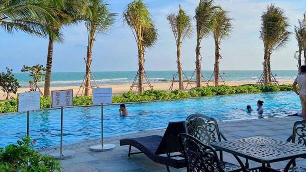 Zona junto a la piscina con sillones de descanso y vistas a la playa.