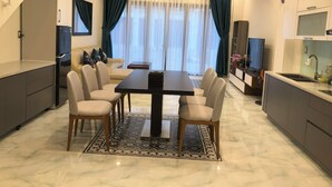 Una cocina moderna con comedor, estufa integrada y un amplio ventanal con cortinas.