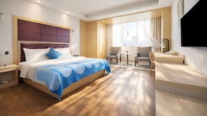 Een moderne hotelkamer met een groot bed, een bureau, een stoel en een televisie.