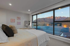 Une chambre avec une grande fenêtre, un lit et une vue sur les montagnes.