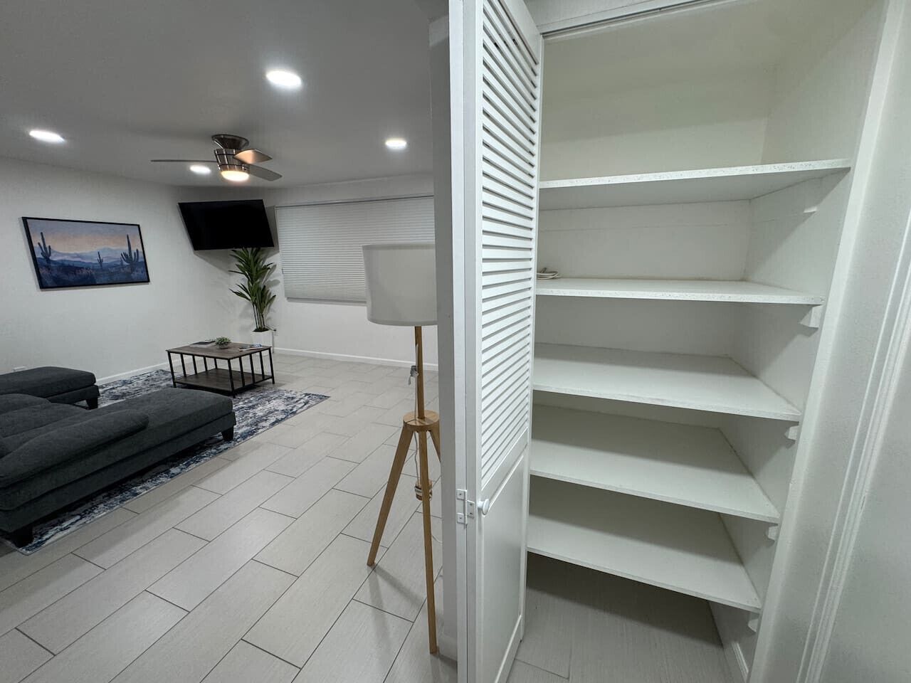 Una sala de estar moderna con un sofá, una lámpara de pie y un televisor en la pared.