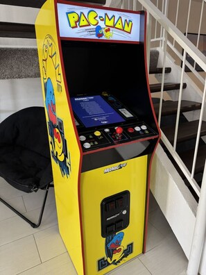 A Pac-Man arcade machine with a yellow and red color scheme, located in a room with a staircase.