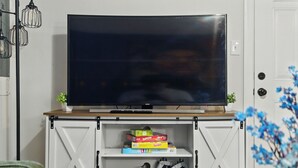 A TV on a wooden shelf with storage cabinets below. - Mountain Bungalow | Nature, History| Wineries|PS5 (Harpers Ferry)