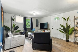 A living room with a sofa, a black armchair, a TV, and a plant. - Mountain Bungalow | Nature, History| Wineries|PS5 (Harpers Ferry)