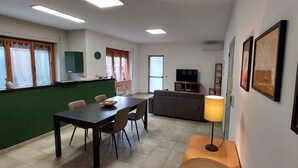 Un salon moderne comprenant un coin repas, un canapé, un téléviseur et une lampe.