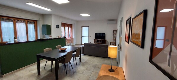 A modern living room with a dining area, a sofa, a TV, and a lamp.