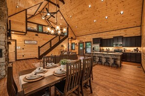 Un intérieur spacieux en bois, comprenant un coin repas, une cuisine et un escalier menant à un niveau supérieur.
