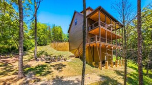 A wooden cabin with a balcony, surrounded by trees and a stone pathway. - Dollywood 28 min | Game Room + Hot Tub + Fire Pit (Sevier County)