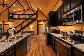 Une cuisine moderne dotée de plans de travail en granit, d’appareils électroménagers en acier inoxydable et d’un intérieur en bois.
