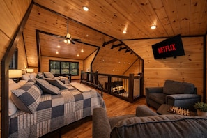 A cozy bedroom with a bed, a chair, a TV, and a balcony.