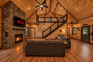 Ein gemütliches Wohnzimmer mit Kamin aus Stein, einer großen Couch, einer Treppe und einem Schild mit der Aufschrift 'Motel'.