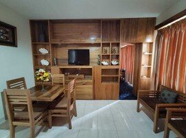 Una sala de estar con un mueble de televisión de madera, una mesa de comedor con sillas y un sofá.