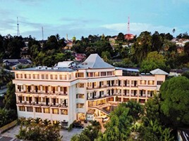 Un hotel de varios pisos con un diseño arquitectónico moderno, que cuenta con balcones y un patio central.
