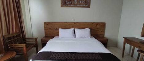 A neatly arranged bedroom with a wooden bed, white bedding, a brown headboard, and a wall-mounted artwork.