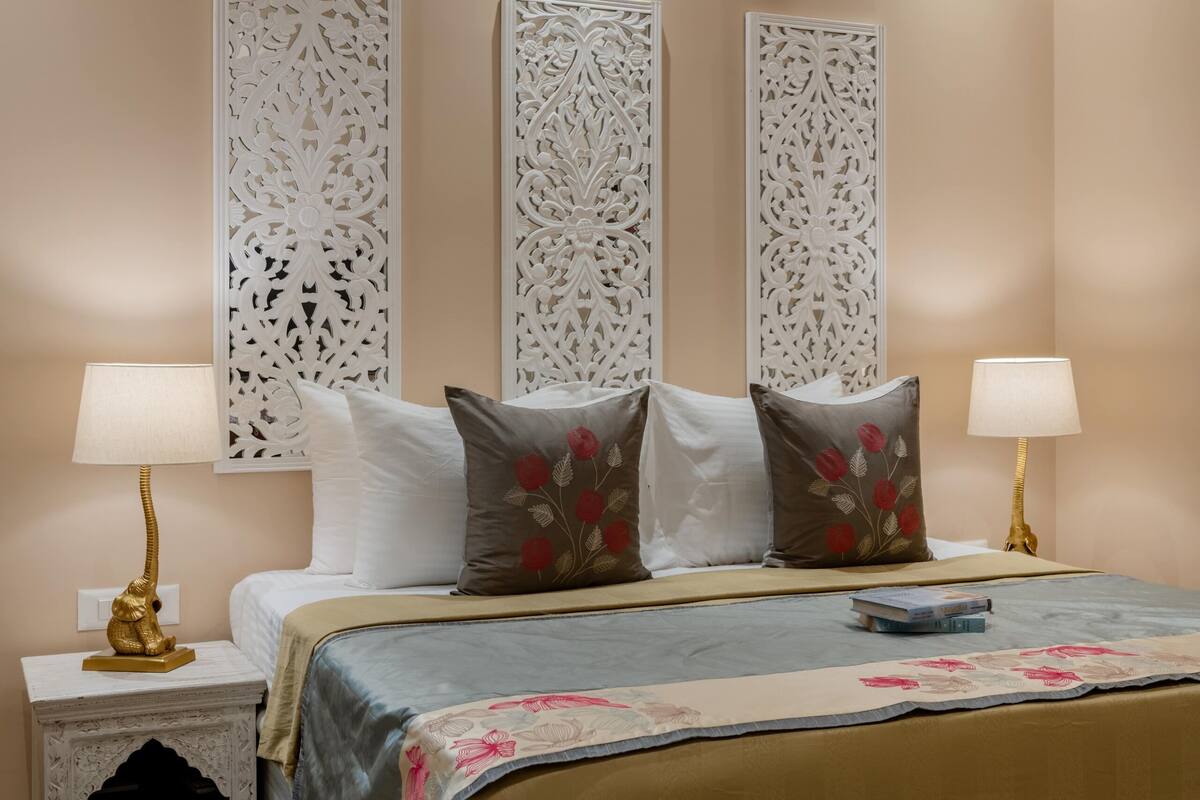 A bedroom with a bed, two bedside tables, decorative wall panels, and a nightstand.
