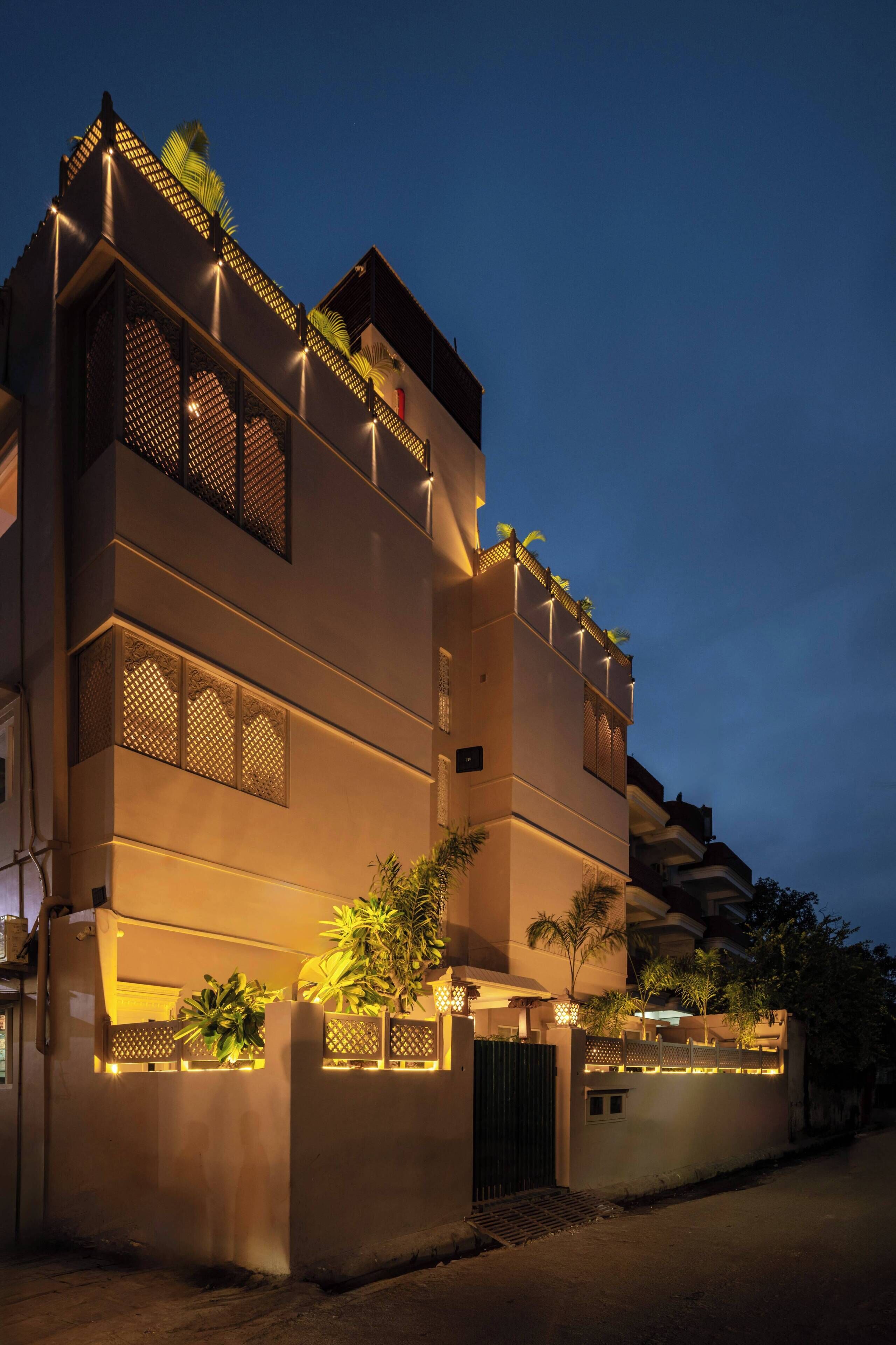 A multi-story building with balconies, a gated entrance, and outdoor lighting.