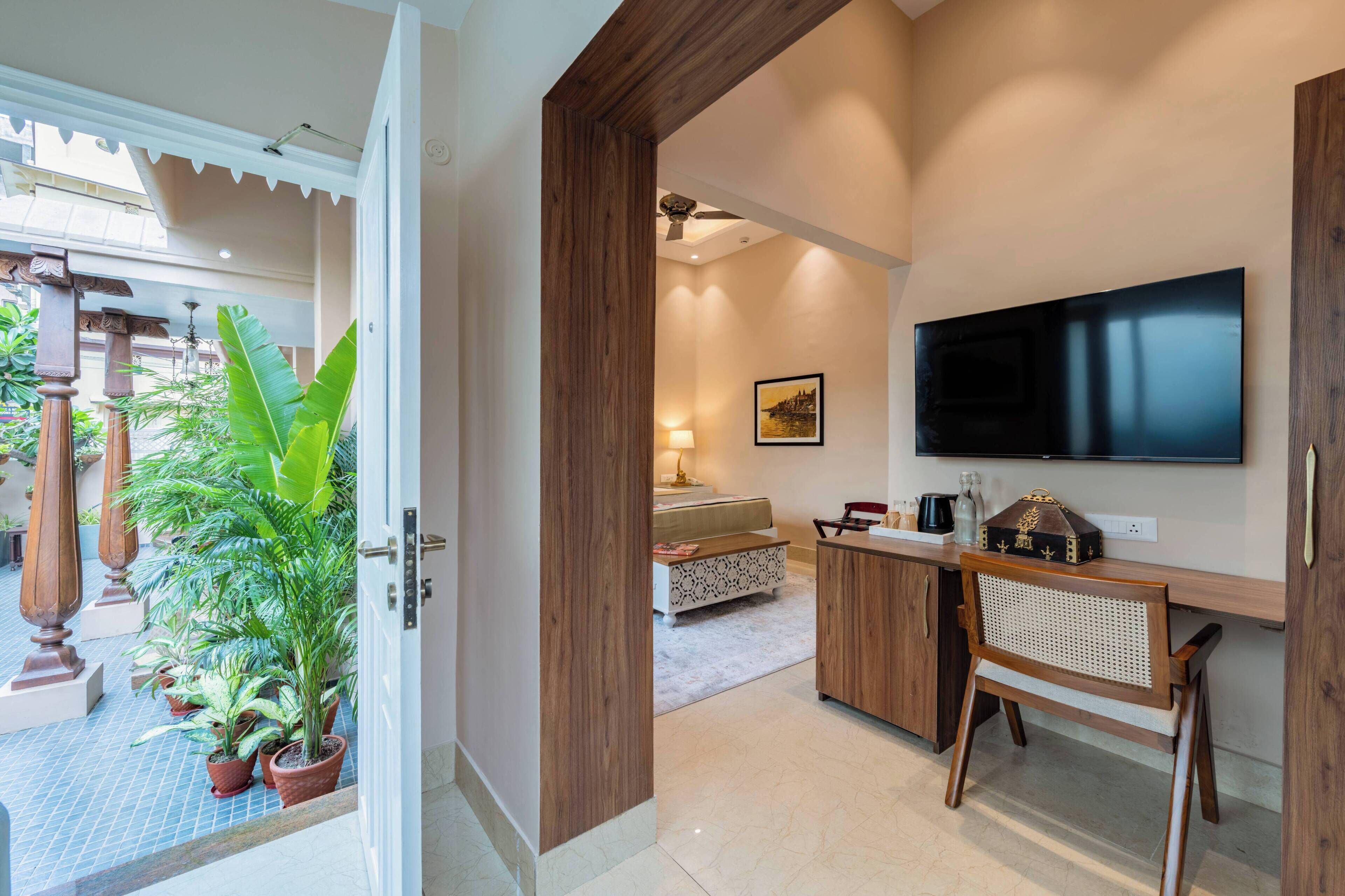 Een moderne hotelkamer met een houten bureau, een flatscreen televisie, een comfortabel bed en uitzicht op de tuin.
