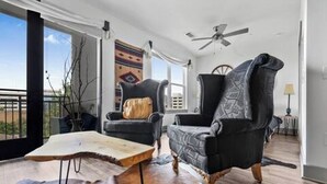 A spacious living room with a large window, a ceiling fan, and a view of the city. - Rustic Luxe Escape, Pool, Parking & Discounts! (Nashville)