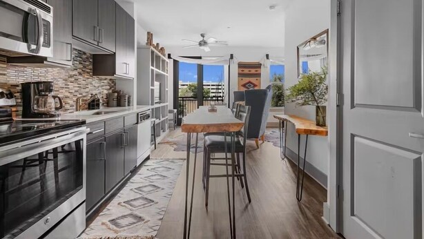 A modern kitchen with dark cabinets, a large stove, and a dining area with a wooden table and chairs. - Rustic Luxe Escape, Pool, Parking & Discounts! (Nashville)