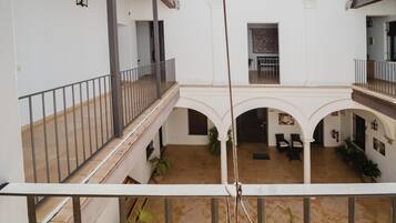 Un amplio patio con varios niveles, con balcones, plantas en macetas y un área central abierta con asientos.