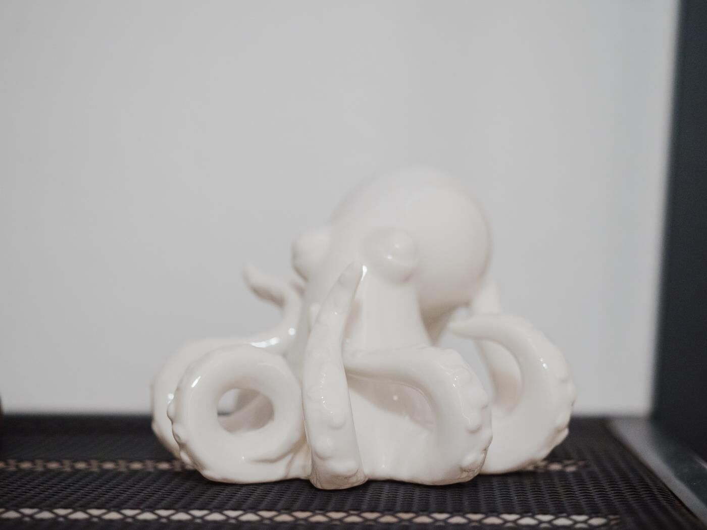 A white ceramic octopus sculpture on a black textured surface.