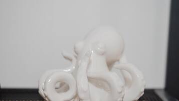 A white ceramic octopus sculpture on a black textured surface.