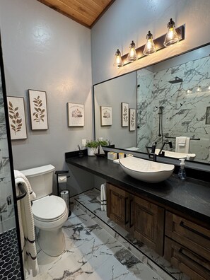 Une salle de bain moderne avec un grand miroir, un lavabo sur colonne et des toilettes.