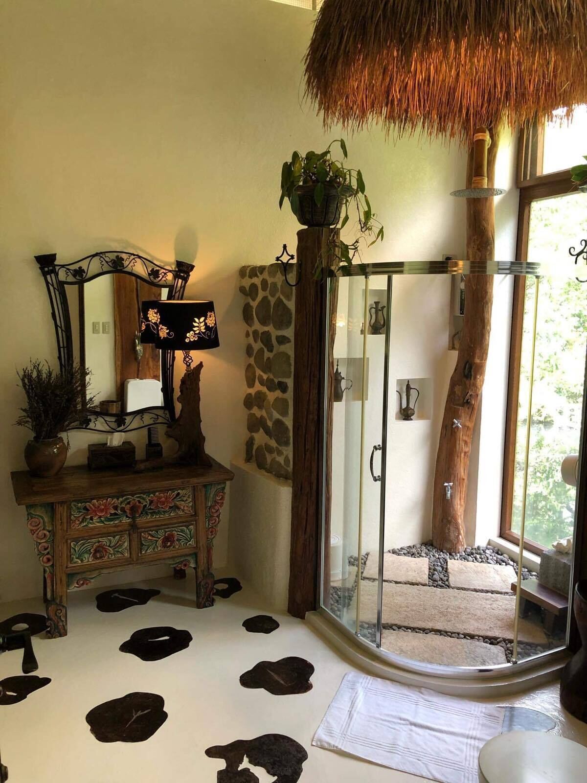 A bathroom with a glass shower enclosure, a wooden vanity with a mirror, and a stone wall.