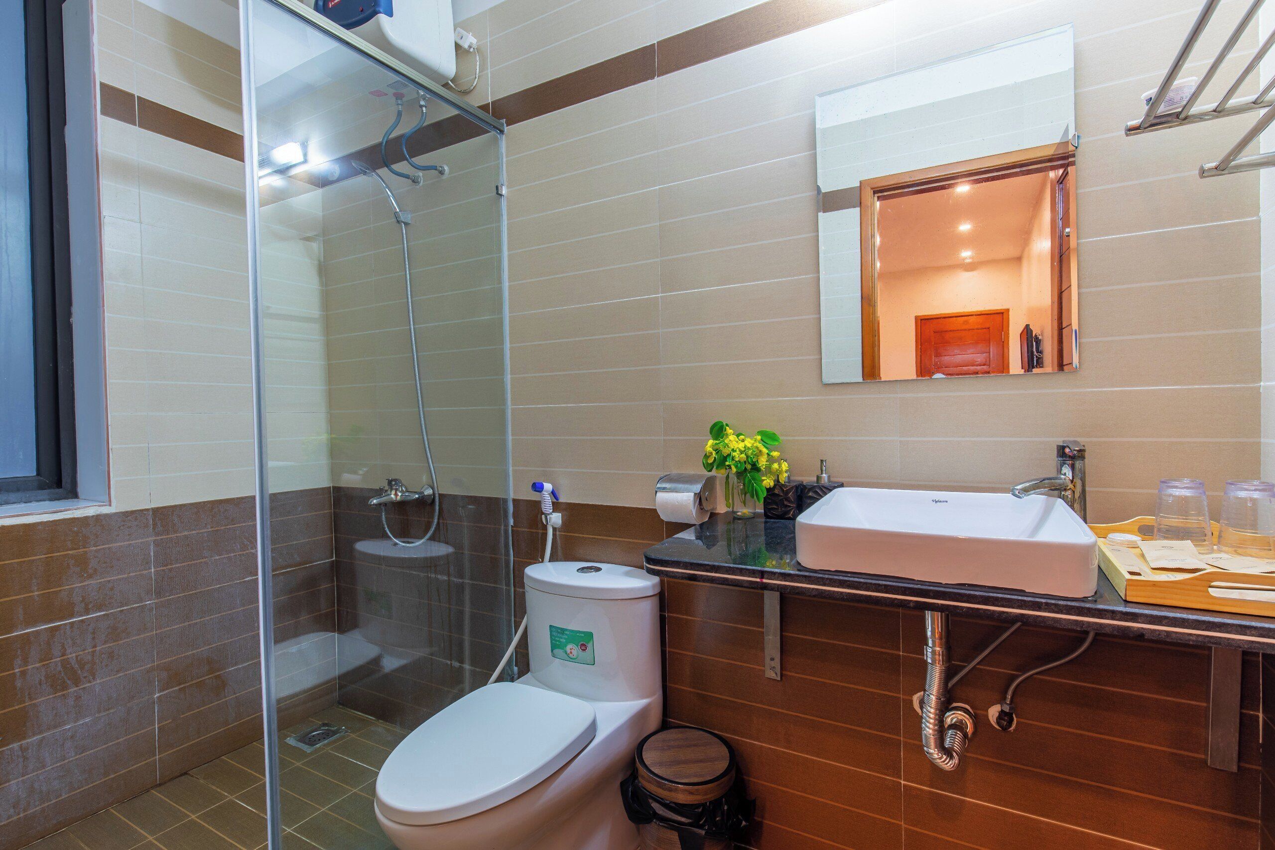 Un baño moderno con ducha de vidrio, inodoro blanco, lavamanos con espejo y tocador de madera.