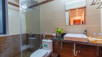 Un baño moderno con ducha de vidrio, inodoro blanco, lavamanos con espejo y tocador de madera.