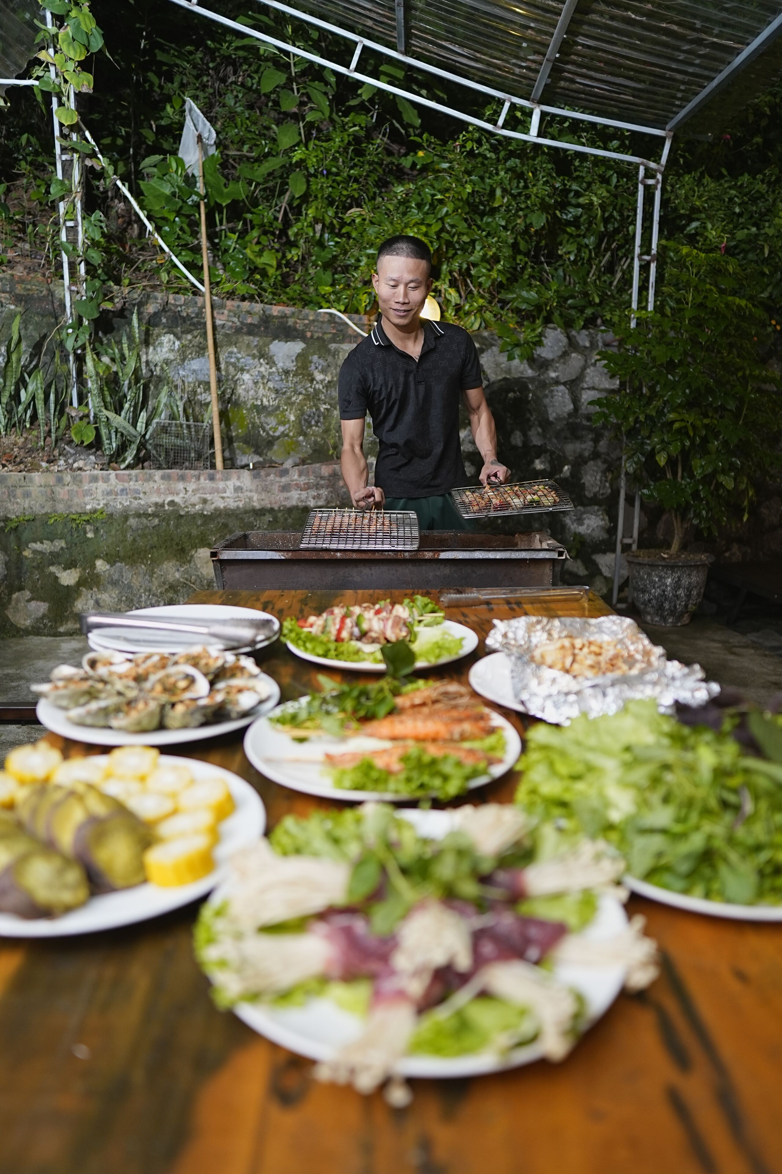 A person grilling food outdoors with various dishes on a table.