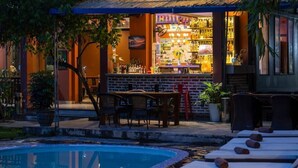 A bar area with a poolside seating arrangement and a bar counter. - Backpackers (Hai Phong)