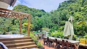 A terrace with a wooden pergola, a dining table with chairs, and a lounge area with a cushioned bench. - Backpackers (Hai Phong)