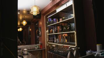 A bar area with shelves of bottles, a counter with glasses, and hanging lights.