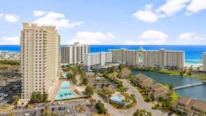 A high-rise hotel with multiple floors, a central swimming pool, and a view of the ocean. - Ariel Dunes II in Seascape Resort! 405 (Miramar Beach)