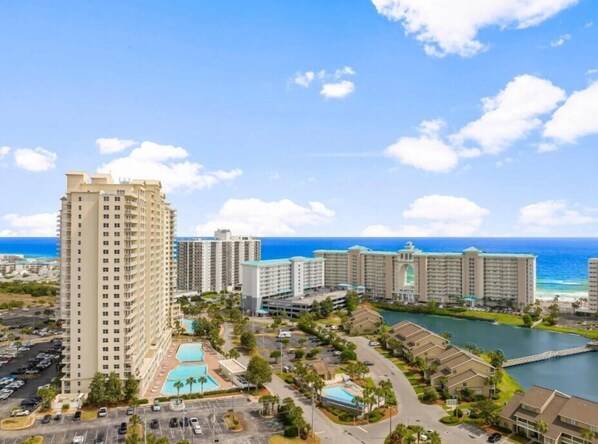A high-rise hotel with multiple floors, a central swimming pool, and a view of the ocean.