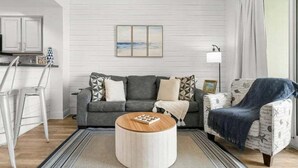 A living room with a grey sofa, a round coffee table, and a patterned armchair. - Ariel Dunes II in Seascape Resort! 405 (Miramar Beach)