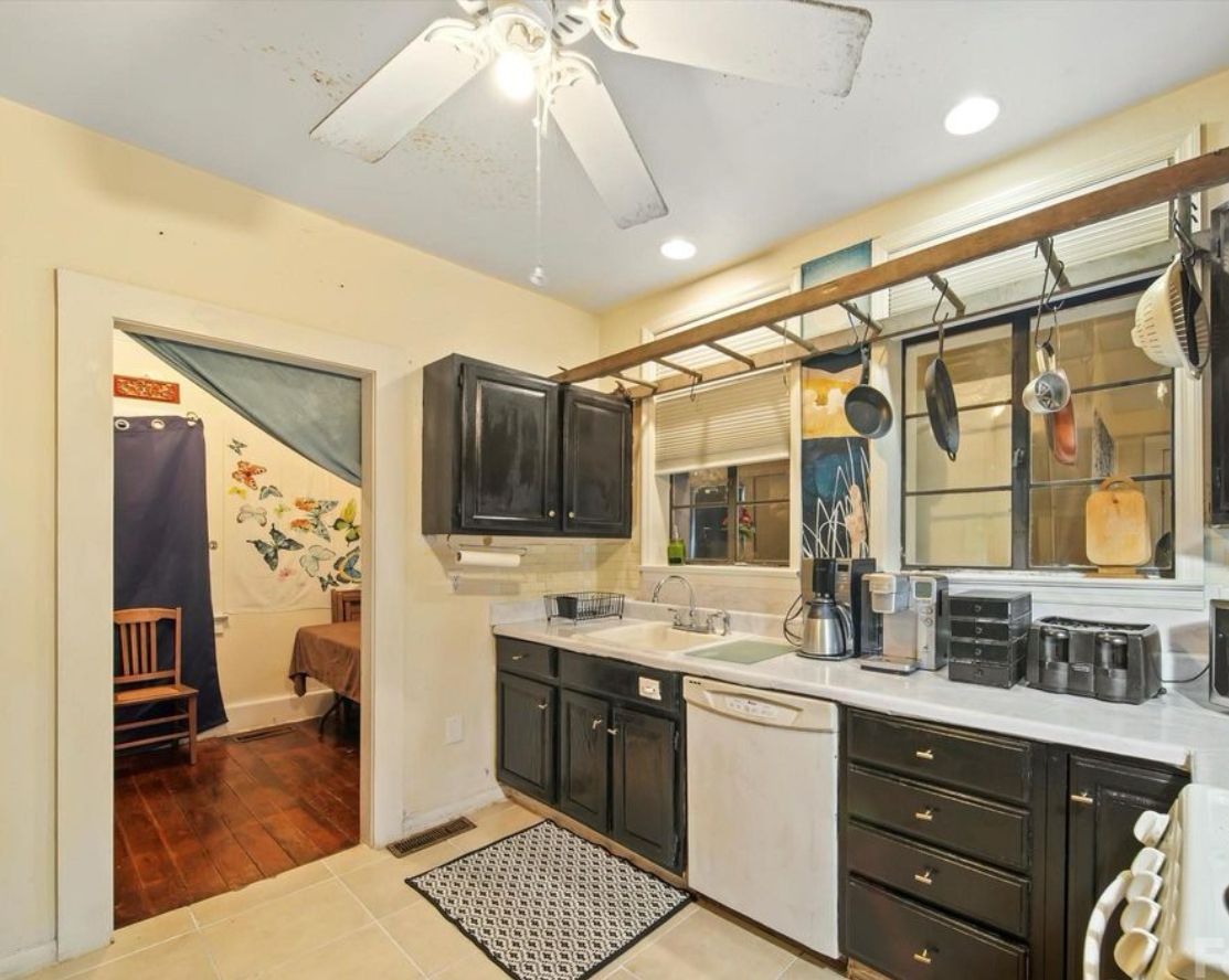 A kitchen with dark cabinets, a white countertop, and a ceiling fan.