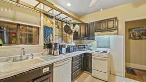 A kitchen with a white stove, a microwave, a sink, and cabinets.