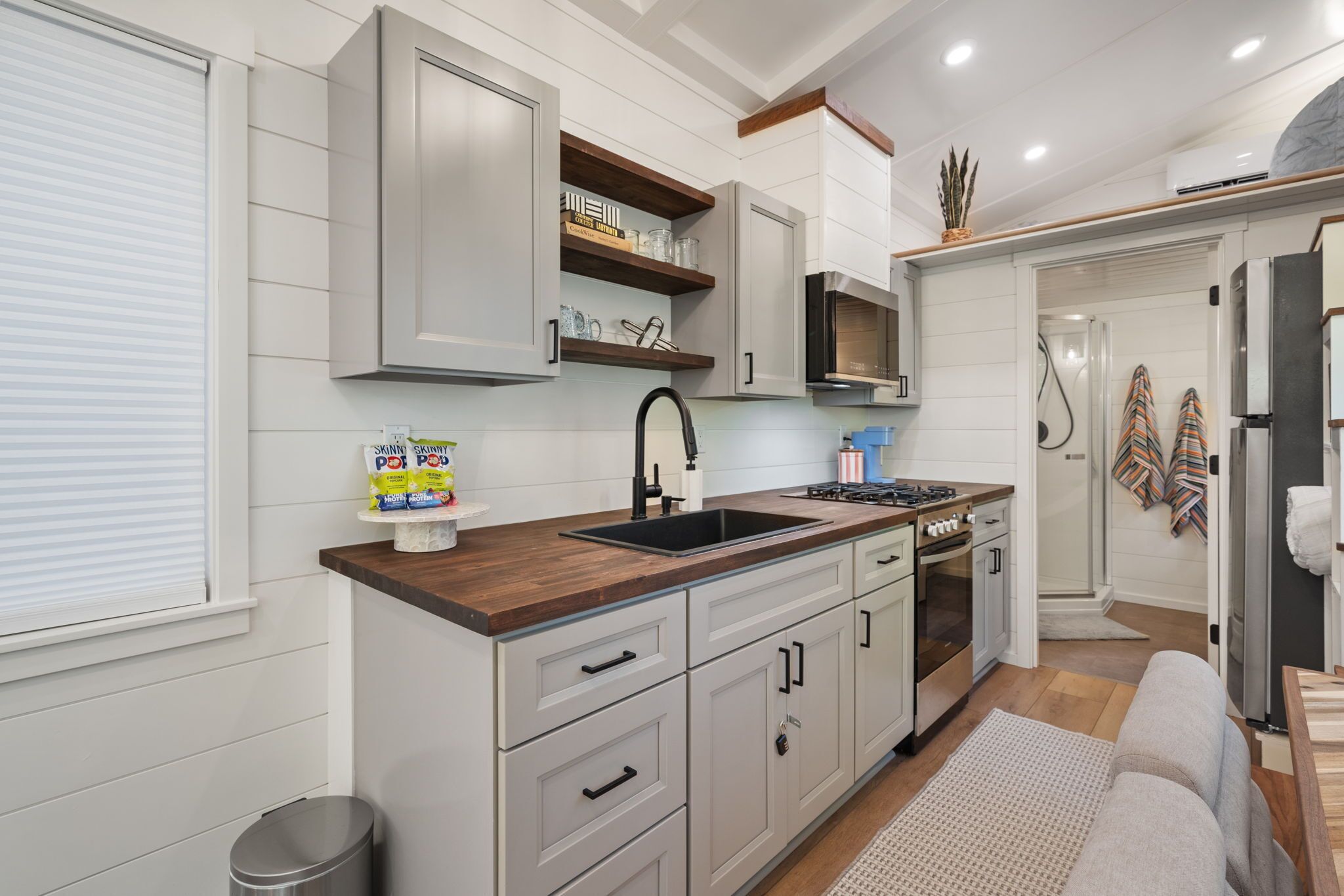 A modern kitchen with white cabinetry, a wooden countertop, and a built-in stove.